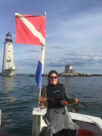 Liz on a boat holding two lobsters