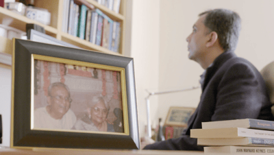 Professor Mihir Desai works in his office alongside a photo of his parents